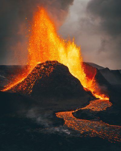 A vertical shot of exploding burning lava near a volcano